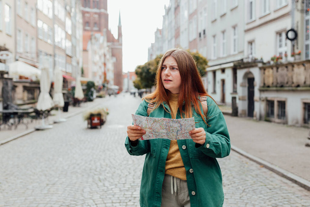Portrait schöne Frau mit Papierkarte auf der städtischen Straße. Junge besorgte Reisende verloren in der Stadt mit Karte - Foto, Bild
