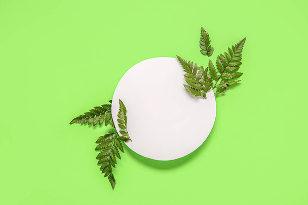 Composición con hoja de papel en blanco y hojas de helecho sobre fondo verde - Foto, Imagen