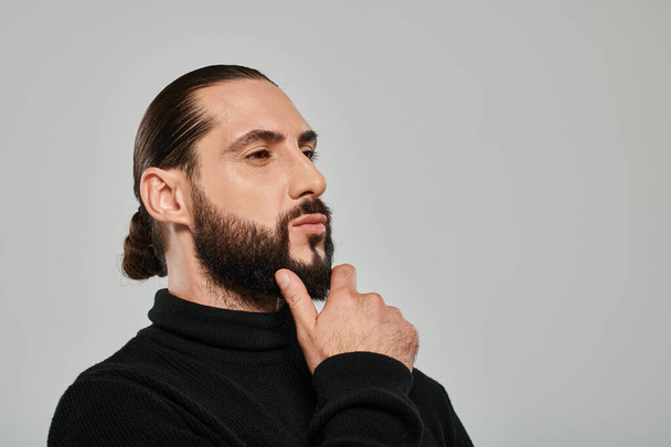 muotokuva hyvännäköinen arabialainen mies poolopaitaa koskettava parta ja poseeraa harmaa tausta - Valokuva, kuva