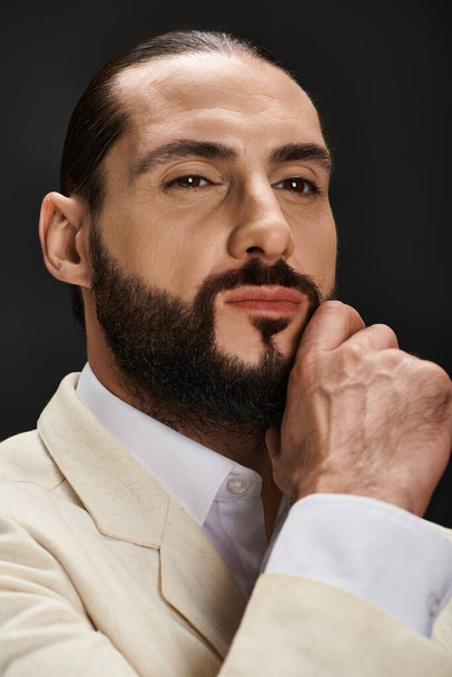 Nahaufnahme Porträt eines bärtigen und selbstbewussten arabischen Mannes in eleganter Kleidung, der vor schwarzem Hintergrund posiert - Foto, Bild