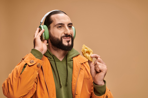 hombre alegre en auriculares con miel baklava sobre fondo beige, postre de Oriente Medio - Foto, imagen