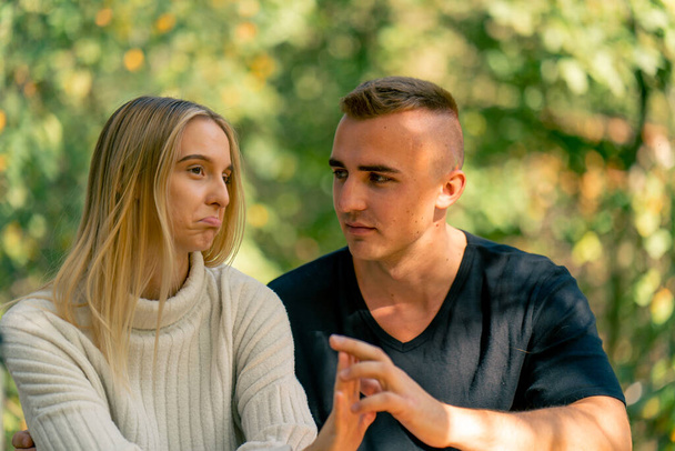 Um jovem casal um cara e uma menina estão falando seriamente enquanto se sentam juntos em um dia ensolarado na natureza - Foto, Imagem