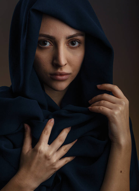 Mladý muslim žena model v ležérní oblečení a tradiční černý hidžáb s úsměvem a při pohledu na kameru přes tmavě šedé pozadí, kopírovat prostor - Fotografie, Obrázek
