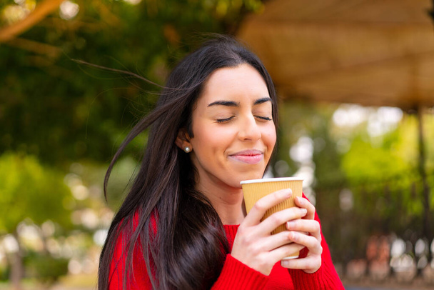 Giovane donna che tiene un caffè da asporto all'aperto - Foto, immagini