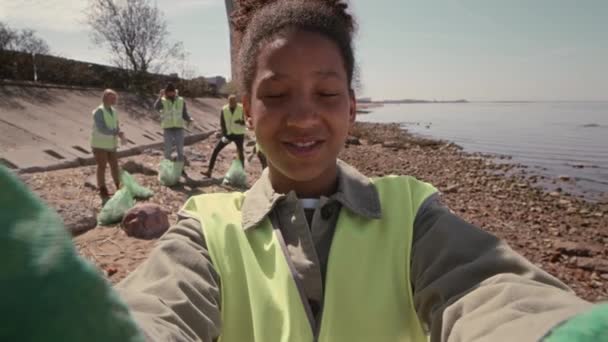 POV toma de voluntaria ambiental afroamericana mirando la cámara y hablando mientras filma vlog sobre limpieza de costa - Imágenes, Vídeo
