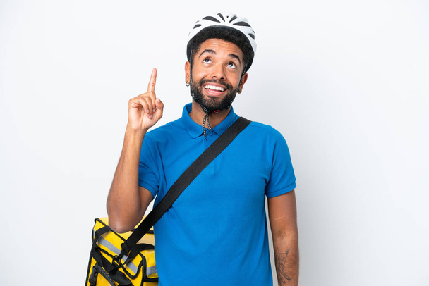 Young Brazilian man with thermal backpack isolated on white background pointing up and surprised - Photo, image