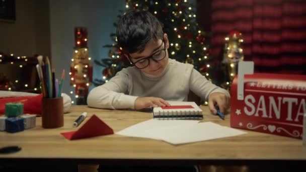 Jonge jongen zet brief voor de Kerstman in de envelop .  - Video
