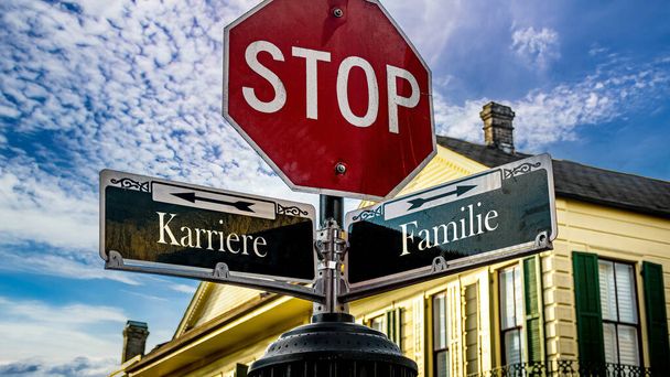An image with a signpost pointing in two different directions in German. One direction points to family, the other points to career. - Photo, Image