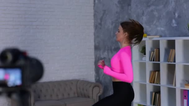 Spor giysili formalı kadın paspas kullanıyor ve evdeki odada koşuyor, kamerayla tripod çekiyor. Kardiyo antrenmanı. Spor, spor konsepti. Gerçek zamanlı video. - Video, Çekim