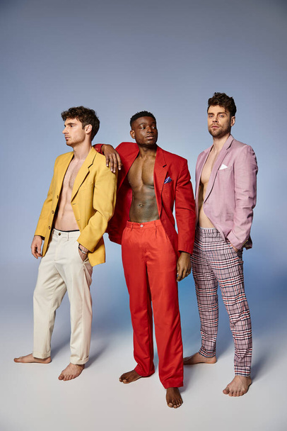 good looking multiracial friends in unbuttoned bright suits on gray background, fashion concept - Fotografie, Obrázek
