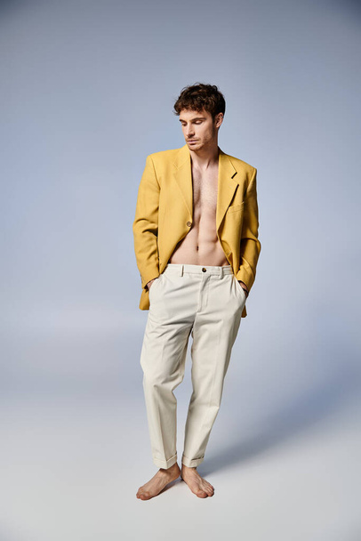ansprechender stylischer Mann in gelber Jacke, der vor grauem Hintergrund attraktiv posiert, Modekonzept - Foto, Bild