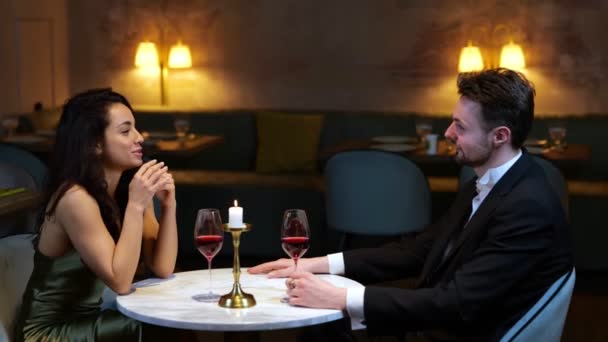 Romantisches Paar, das sich im Restaurant unterhält und verabredet, während die Kellnerin ein Menü mitbringt. Lebensstil, Liebe, Beziehungskonzept. Echtzeit-Video. - Filmmaterial, Video