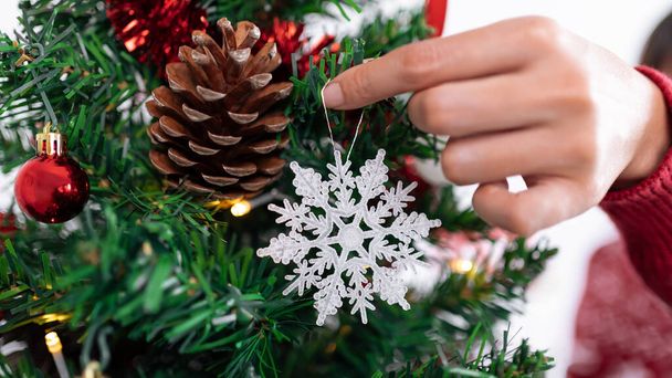 Азиатка украшает рождественскую елку красивой снежинкой. Девушка украшена праздничные снежные звезды Xmas украшения. Новогодний элемент дизайна - Фото, изображение