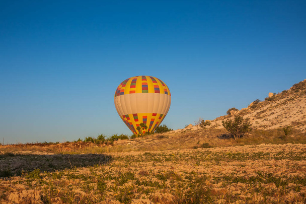 Los globos de aire caliente despegan del suelo temprano en la mañana. Globos de aire caliente volando sobre extraños paisajes rocosos en Capadocia. Hermosos globos de aire caliente en el cielo de la mañana. Goreme. Turquía - Foto, Imagen