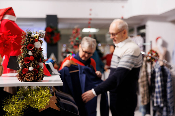 ラックにスーツジャケットをレビューする顧客の選択的な焦点は,クリスマスイブディナーで着用するお祝いの服を探しています. 小売店でブレザー生地をチェックする人,正式な服装アウトレット. - 写真・画像