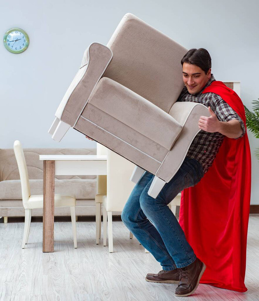 Süper kahraman evde mobilya taşıyor. - Fotoğraf, Görsel