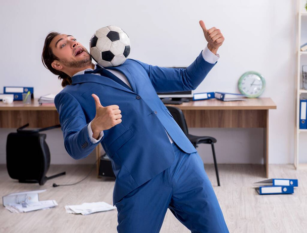 Młody pracownik gra w piłkę nożną w biurze - Zdjęcie, obraz