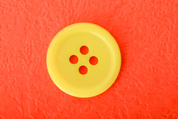 Желтая кнопка шитья изолирована на красном фоне. - Фото, изображение