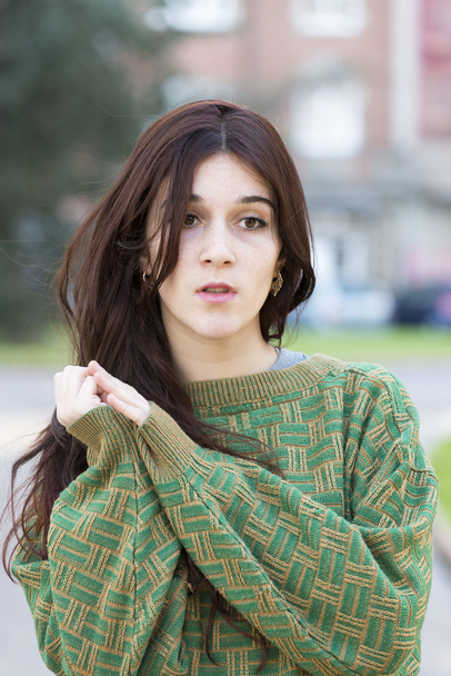 Pensive beautiful young woman with green sweater, outdoor. - Photo, Image