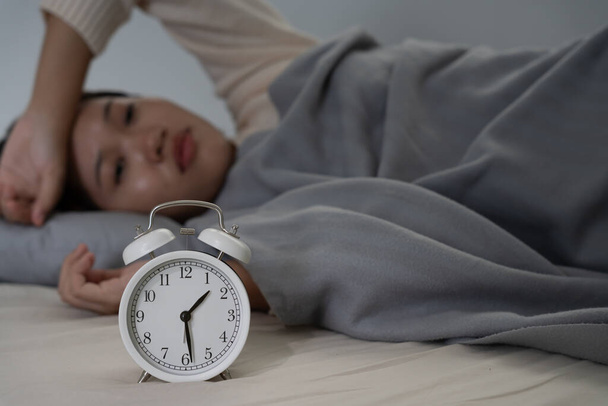 mulher asiática na cama tarde tentando dormir sofrendo insônia, sem dormir ou com medo em um pesadelo, parecendo triste preocupado e estressado. Cansado e dor de cabeça ou enxaqueca acordando no meio da noite. - Foto, Imagem