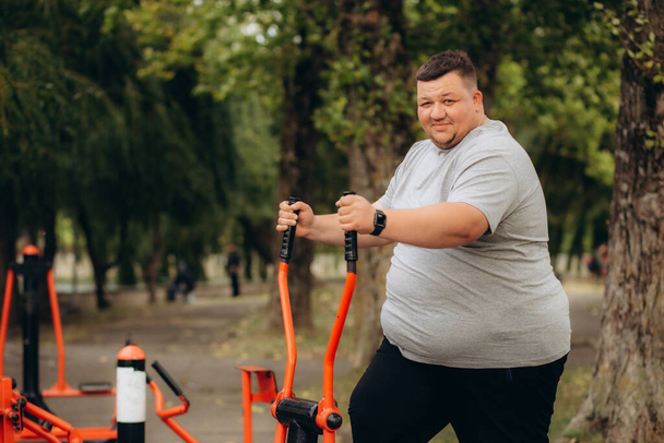 a fat man loses weight on an exercise bike - Photo, Image