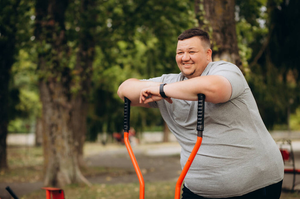 um homem gordo perde peso em uma bicicleta de exercício - Foto, Imagem