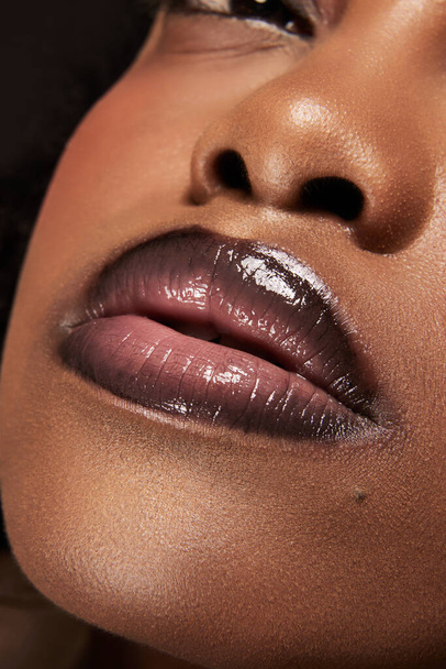 よく保たれた肌で女性の顔の写真をクローズアップ. アフリカ系アメリカ人女性の唇が光る完全なプランプ. 光沢のある口紅。 美容,化粧品,スパトリートメント,化粧品のコンセプト。 アドベンチャー - 写真・画像