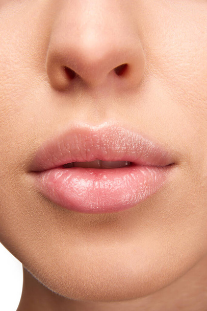 Täydellinen luonnollinen huulimeikki. Lähikuva kuva naisen huulet kiiltävä huulipuna. Kosteuttava kaveri tikku kuiville huulille. Käsitys kauneudesta, meikistä, kosmetiikasta, kylpylähoidoista, kosmeettisista valmisteista. Ilmoitus - Valokuva, kuva