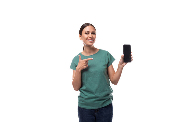 Tişörtü ve kotu siyah saçlı, ince, beyaz bir kadın akıllı bir telefon ve bir model gösteriyor.. - Fotoğraf, Görsel