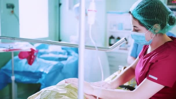 Egy nő, aki a szülészeten szül. Egy terhes nő, aki kórházban szül, sír. Orvosok csapata fejezi be a műtétet a szülészeten. Terhesség, szülés - Felvétel, videó