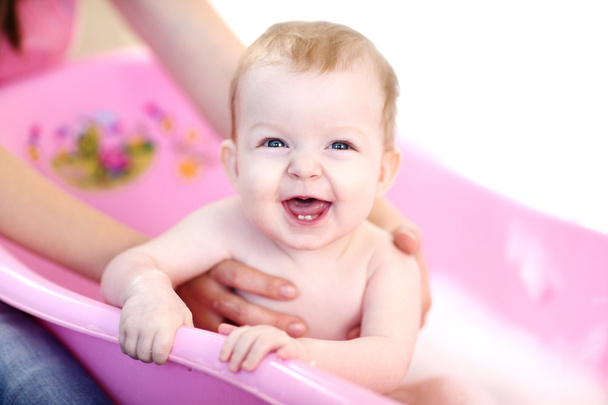 Mother washing a baby in pink bathtub - Photo, Image