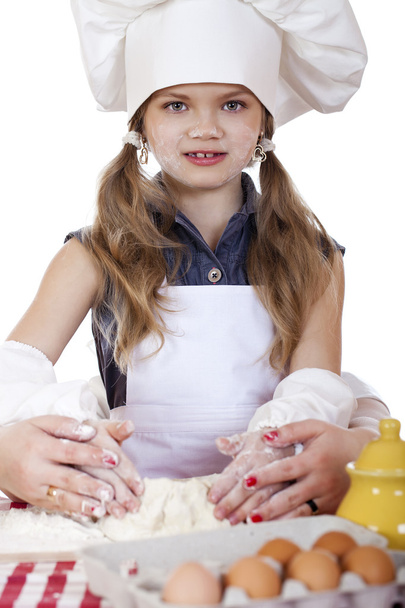 Little girl in a white apron and chefs hat knead the dough in th - Foto, Imagem