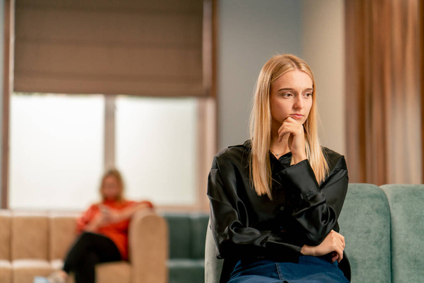 Retrato de una chica triste y pensativa que está sentada en el vestíbulo del hospital y esperando a su médico - Foto, Imagen