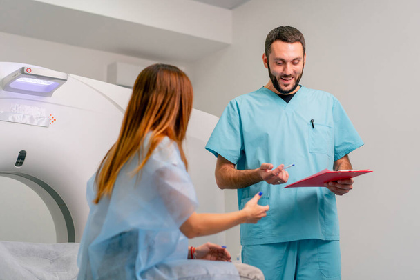 Un radiólogo describe a una paciente los resultados de su examen después del diagnóstico mediante una máquina de resonancia magnética. - Foto, Imagen