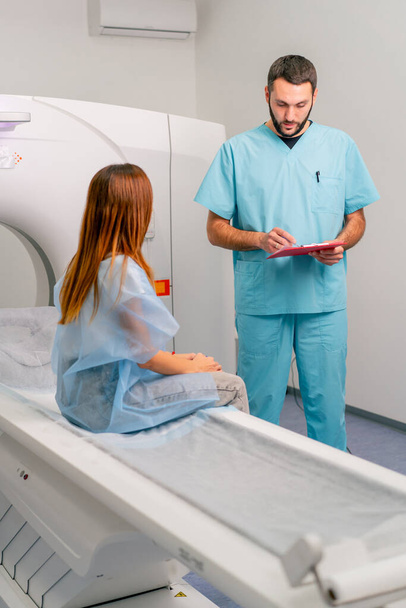 Ένας ακτινολόγος περιγράφει σε μια ασθενή τα αποτελέσματα της εξέτασής της μετά τη διάγνωση χρησιμοποιώντας ένα μηχάνημα μαγνητικής τομογραφίας - Φωτογραφία, εικόνα