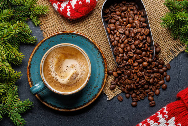Кофейная чашка, жареные кофейные зёрна и елки в уютной обстановке. Рождественская открытка - Фото, изображение