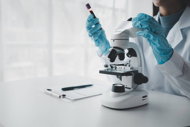 Chemik používá mikroskop k hledání chemikálií z krve ve zkumavce, Vědecký experiment hledá biologické odpovědi v laboratoři, laboratorní nápad. - Fotografie, Obrázek