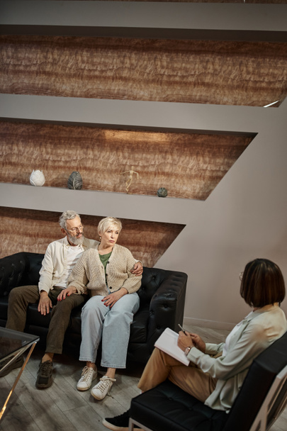 szakállas férfi ölelés aggódó középkorú feleség terápiás ülés során családi tanácsadó - Fotó, kép