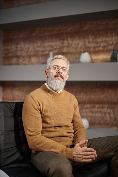 pohledný psycholog středního věku v brýlích sedí na křesle během terapie - Fotografie, Obrázek