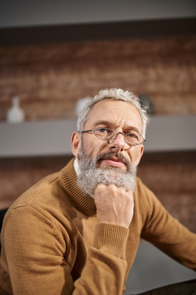 Porträt eines gutaussehenden Psychologen mittleren Alters mit Brille, der während einer Therapiesitzung in die Kamera blickt - Foto, Bild
