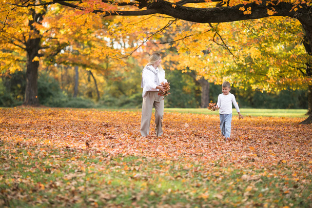 Día de las madres, familia del amor. Familia en otoño paseo en la naturaleza al aire libre. Madre e hijo con ternura abrazadora - Foto, imagen