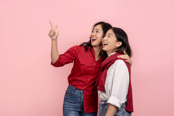 Красивая азиатская женщина в красной рубашке, указывая, чтобы отправить сообщение изолированных привлекательных и веселых азиатских женщин, обнимающих друг друга на розовом фоне. - Фото, изображение