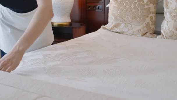 Inclinazione fino colpo di cameriera concentrata al lavoro fare nuove lenzuola in camera d'albergo prima del check-in - Filmati, video
