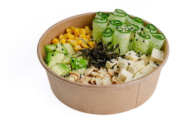 Veganer Poke mit Tofu, Avocado, Mais, Gurken, Erdnüssen, Reis, Aioli-Sauce auf weißem Hintergrund - Foto, Bild