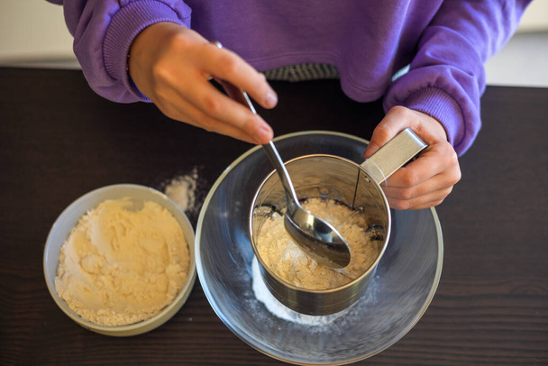Les mains de l'enfant tamisent la farine de près - Photo, image