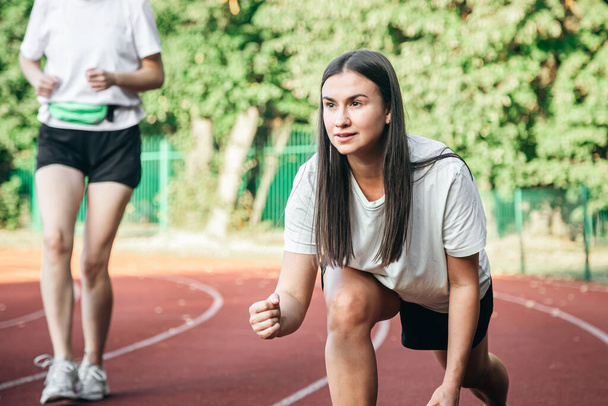 Genç bir bayan koşucu antrenman yaparken koşu pozisyonunda, spor giyimli bir kadın stadyumda koşuyor.. - Fotoğraf, Görsel