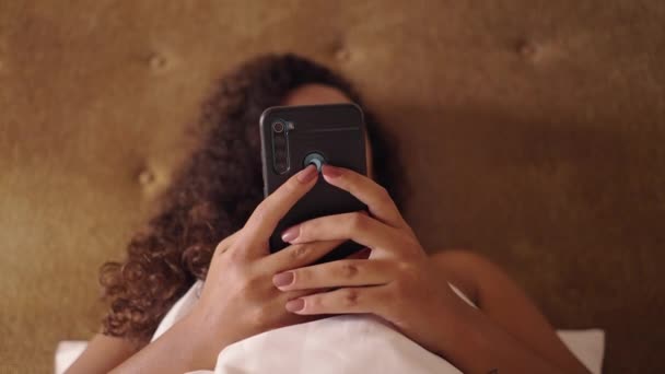 Smartphone est texté par une femme méconnaissable dans un lit - Body Positive - Séquence, vidéo