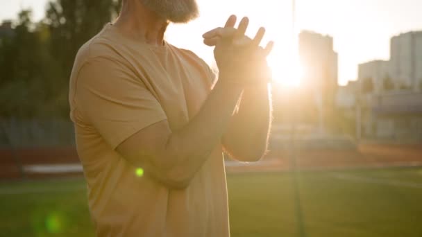 Кавказький літній чоловік розтягує руки, розігріває вправи спорт пенсіонерське місто на свіжому повітрі схід сонця природа ранкова підготовка фітнес-тренування охорона здоров'я старий спортсмен тренування невизначений спосіб життя - Кадри, відео