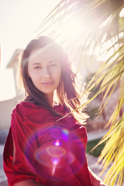 Palmiye ağaçları ve güneş arkadan aydınlatmalı yakınındaki güzel kız - Fotoğraf, Görsel