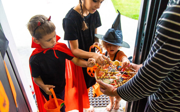 Дети берут конфеты из корзины. Хэллоуин. Селективный фокус. - Фото, изображение